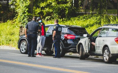 man in black t-shirt and black pants standing beside black suv during daytime